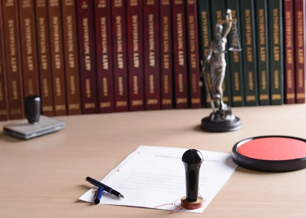 Legal document with notary seal and law books on desk at the Law Office of Desiree Berg